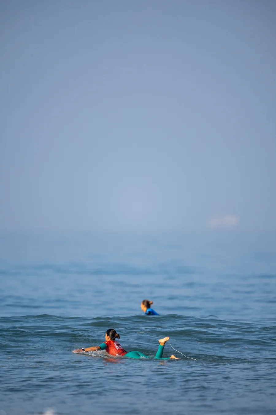 Un surfeur au line-up, hors de portée de voix depuis la plage Deux surfeurs attendant la prochaine vague au line-up